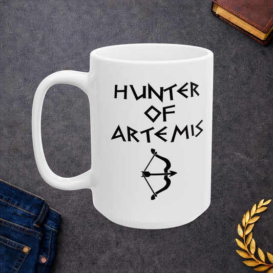 White ceramic mug featuring a minimalist, Greek-inspired graphic in black ink on a white background. The design reads 'HUNTER OF ARTEMIS' in a stylized, angular font, positioned above a clean, line-art graphic of a bow and a notched arrow.
