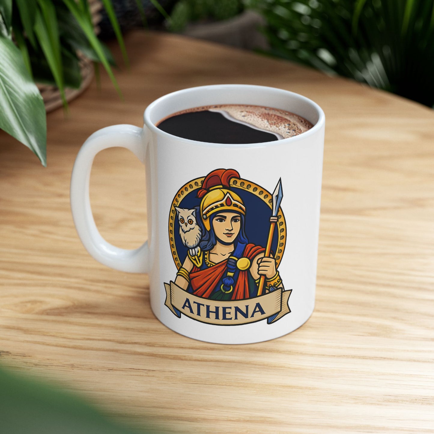White ceramic mug with a vibrant, circular emblem featuring the Greek goddess Athena. She wears a golden helmet with a red crest and holds a spear, with a small white owl perched on her shoulder. The design is set against a dark blue background with a gold dotted border. A parchment-style banner at the bottom displays the name "ATHENA" in bold capital letters. The illustration has a clean, modern vector art style.