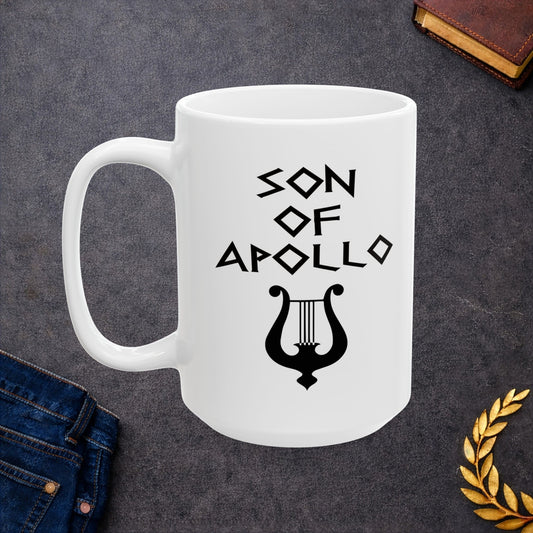 White ceramic mug featuring a minimalist, Greek-inspired graphic in black ink on a white background. The design reads 'SON OF APOLLO' in a stylized, angular font, positioned above a clean, line-art graphic of a classical lyre.