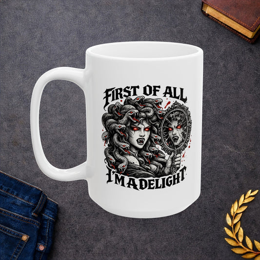Gothic streetwear illustration of Medusa on a ceramic white mug. Black and white engraving features the figure with serpents for hair, each snake with glowing red eyes. She holds an ornate mirror reflecting her fierce expression with matching red-eyed gaze. Text reads 'First of All, I'm A Delight' in bold metal lettering. Red accents highlight the snakes' eyes. Clever wordplay blends mythology with modern sarcastic humor and confidence.