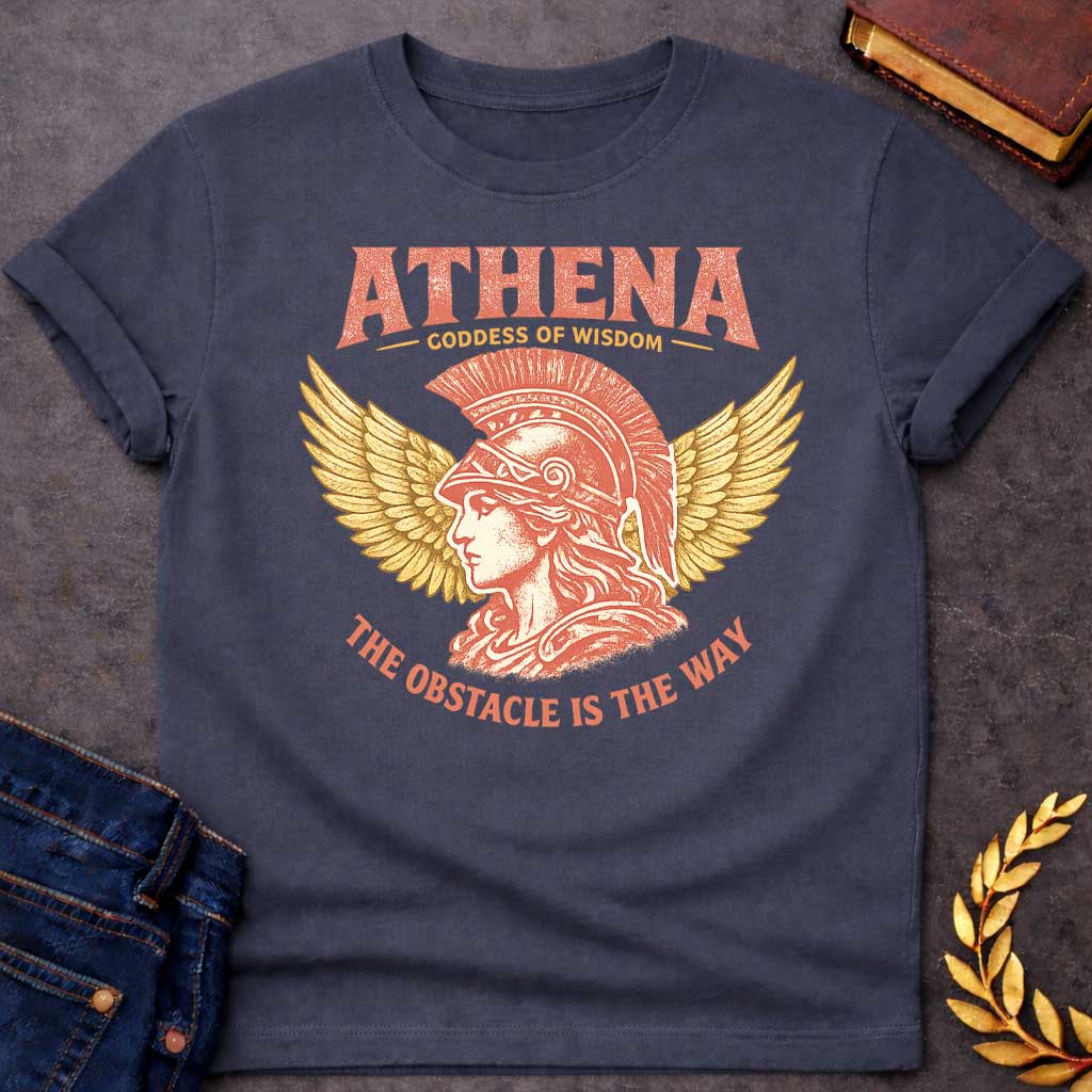 Dark Heather t-shirt graphic featuring a side-profile illustration of Athena wearing a Corinthian helmet with a red plume, flanked by large golden wings. Text reads "ATHENA – Goddess of Wisdom" arched above and "The Obstacle Is the Way" curved below, in a vintage Greek mythology style with rose and gold tones