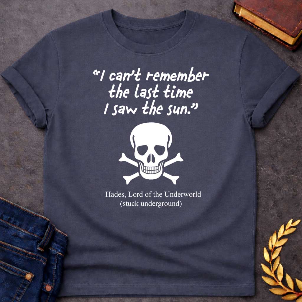 Dark Heather T-shirt graphic in black and white featuring a handwritten-style quote reading "I can't remember the last time I saw the sun." above a classic skull and crossbones illustration, with the humorous attribution below reading "- Hades, Lord of the Underworld (stuck underground)