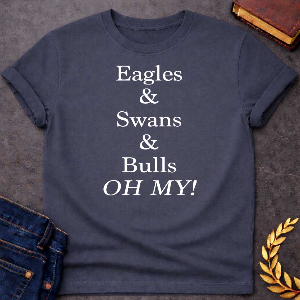 Dark Heather T-shirt graphic in white featuring large bold serif text reading "Eagles & Swans & Bulls OH MY!" — a humorous parody of the "Lions and Tigers and Bears, Oh My!" phrase from The Wizard of Oz, referencing the many animal disguises Zeus used for his romantic pursuits in Greek mythology
