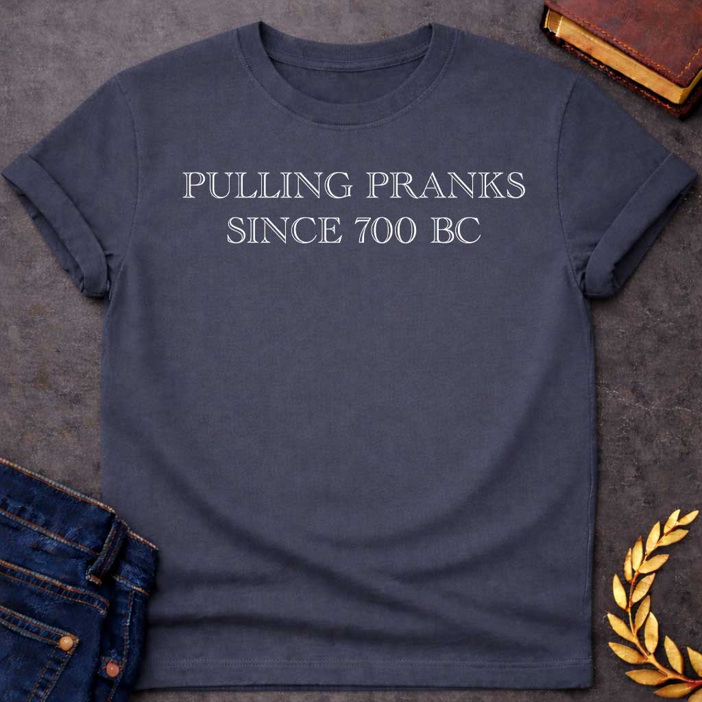 Dark Heather T-shirt graphic in white text featuring large outlined engraved-style serif text reading "Pulling Pranks Since 700 BC" — a humorous nod to Hermes, the Greek Messenger God and notorious trickster
