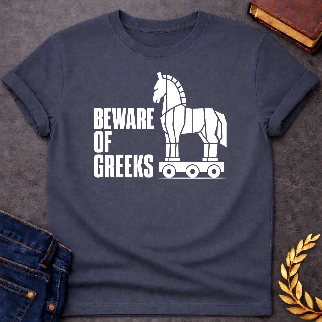 Dark Heather T-shirt with a graphic in white featuring bold condensed sans-serif text reading "Beware of Greeks" alongside a flat geometric white silhouette illustration of the Trojan Horse mounted on a wheeled platform — a humorous reference to the Greek legend of the Trojan War
