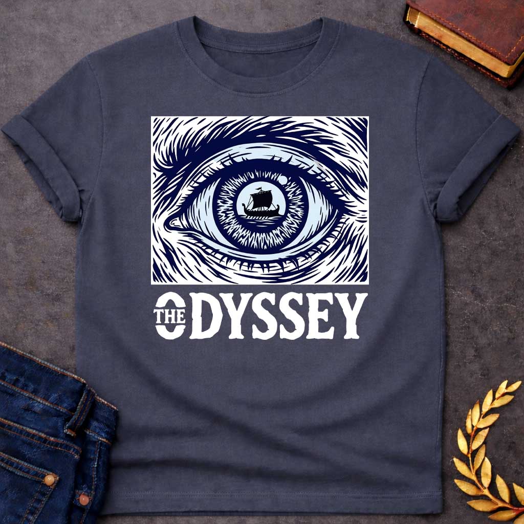 Dark Heather T-Shirt with a dramatic graphic design for 'The Odyssey' featuring a stylized eye in navy blue and white. The iris contains a silhouette of an ancient Greek ship with a single sail, surrounded by radiating lines suggesting both an iris pattern and oceanic waves. Swirling, turbulent linework evokes stormy seas and Odysseus's tumultuous journey. Bold serif text reads 'THE ODYSSEY' in white. Combines classical maritime imagery with modern design, emphasizing vision, journey, destiny, and fate.