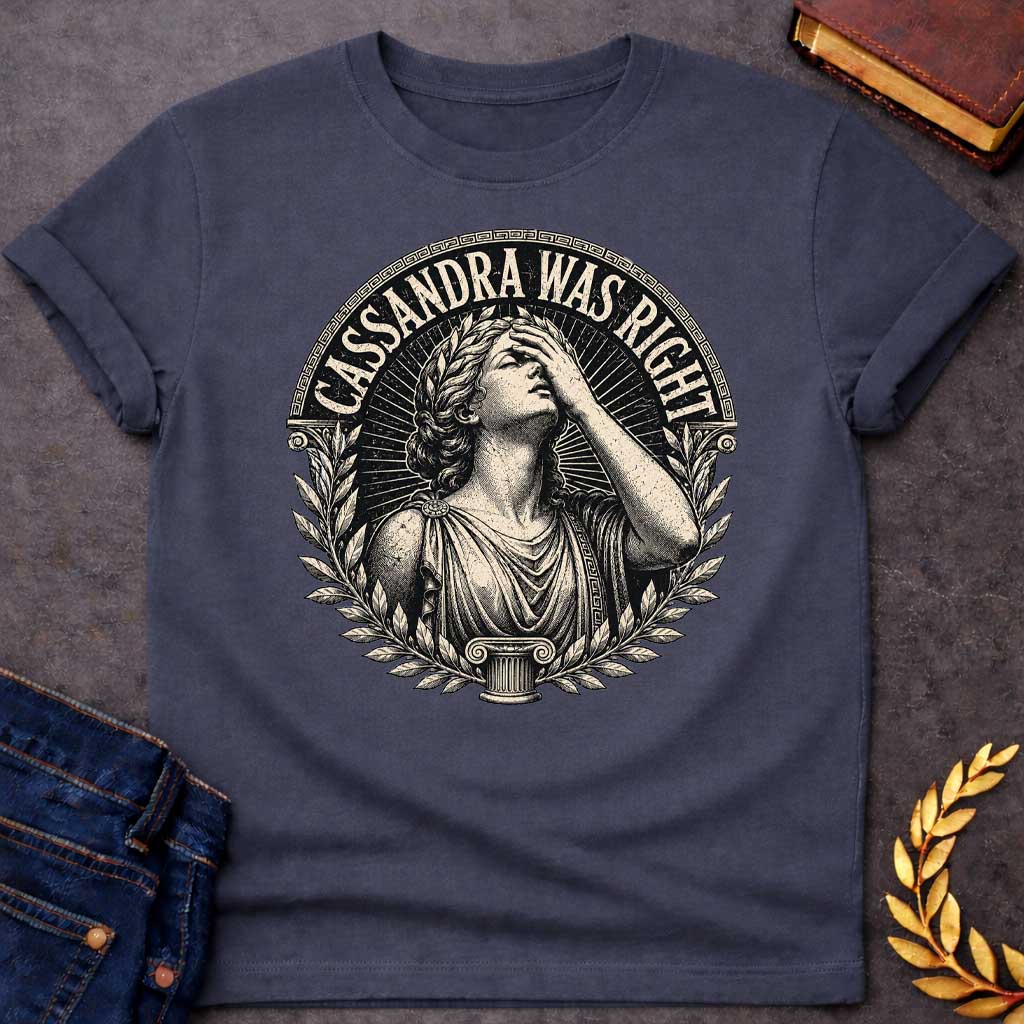 Dark Heather T-shirt with a classical engraving-style illustration of Cassandra, the Trojan prophetess, looking upward with one hand raised to her forehead in anguish. She wears flowing Greek robes with decorative brooch and Greek key pattern trim. Surrounded by laurel wreaths and flanked by Ionic columns. Radiating lines create a dramatic halo effect. Text 'CASSANDRA WAS RIGHT' curves along the top within a Greek key border. References the tragic myth of Cassandra, cursed to see the future but never be bel