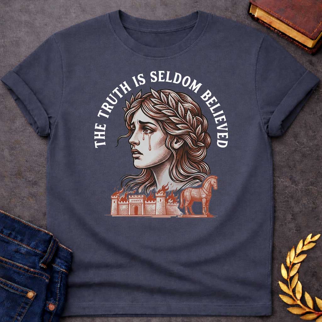 Dark Heather T-shirt with a A Greek mythology design featuring a detailed woodblock-engraving style illustration of a crying Cassandra in profile. She wears a laurel wreath, with tears streaming down her face. Arched above her is the text "THE TRUTH IS SELDOM BELIEVED" in a bold white serif font. Below her portrait, a burning ancient city wall and the Trojan Horse are illustrated in a fine-line, terracotta-orange style.