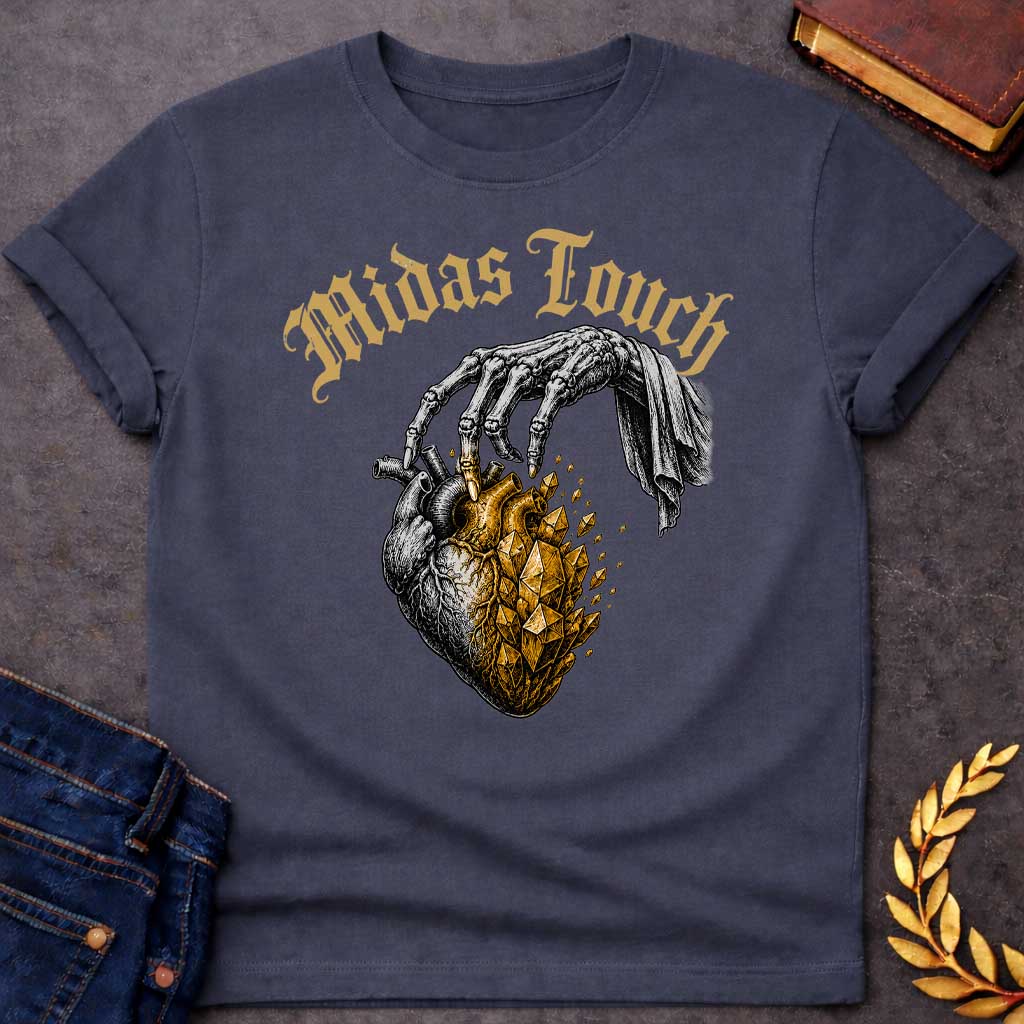 Dark Heather t-shirt with A Vintage engraving-style Greek mythology design featuring a skeletal hand with the Midas touch transforming half of an anatomical heart into shimmering gold crystals. Above the illustration, gothic lettering reads "Midas Touch." Inspired by the tragic King Midas myth, the design symbolizes how greed and the pursuit of wealth can harden the heart, using bold black and metallic gold artwork.