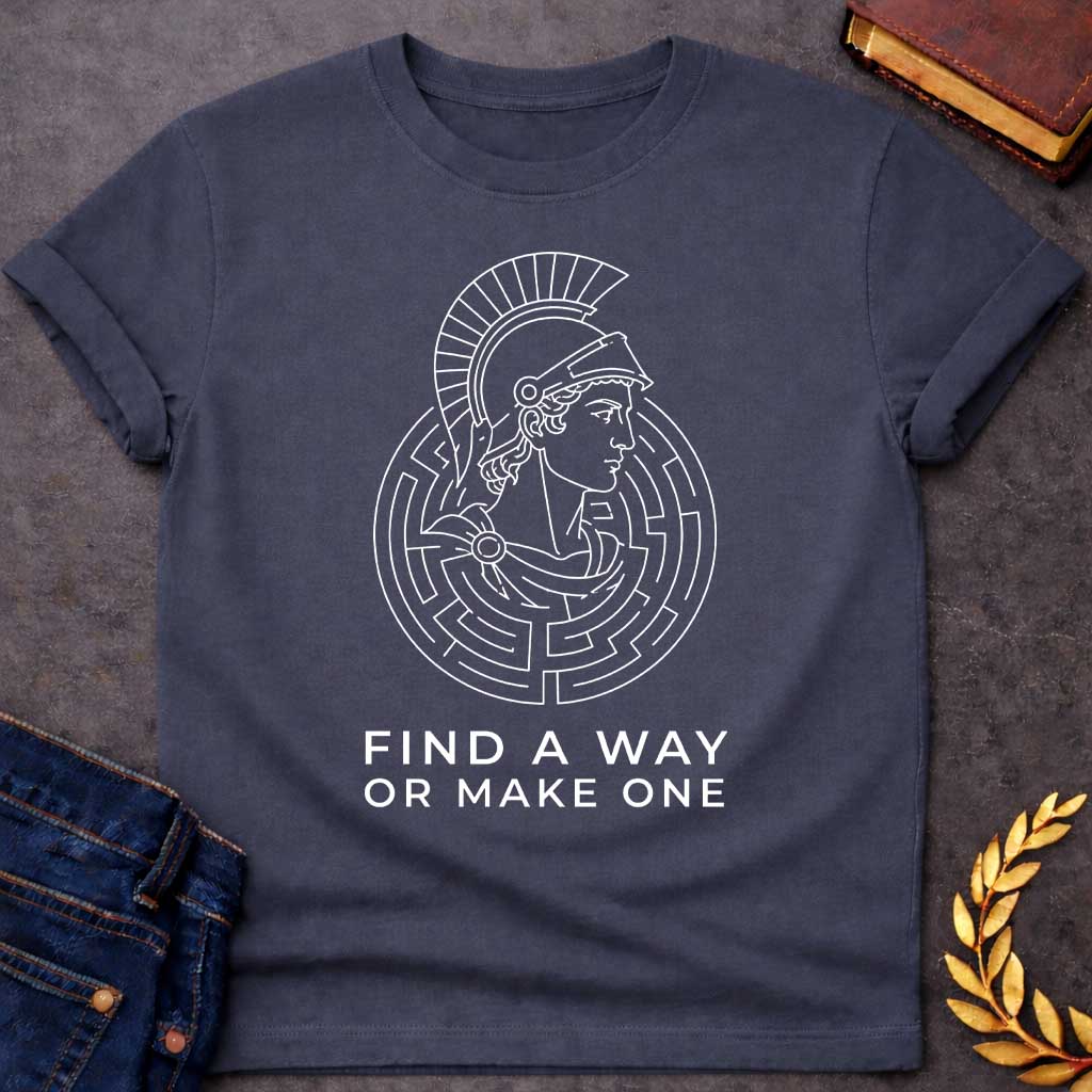 Dark Heather T-shirt with A Classical profile of a Spartan warrior wearing a crested Corinthian helmet, surrounded by concentric circular maze patterns forming an intricate labyrinth. Black and white line art style. Text reads 'Find A Way Or Make One' below. Motivational design celebrating determination, problem-solving, and perseverance. References Theseus's escape from the mythological Cretian labyrinth while embodying warrior resilience and grit.