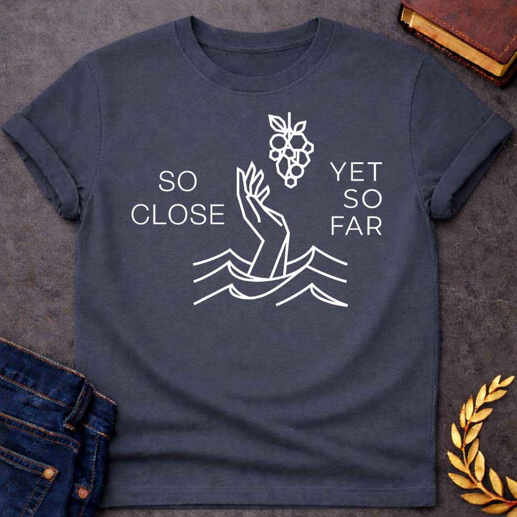 Dark Heather t-shirt with A minimalist, geometric line-art design. Rendered in crisp white lines, a stylized hand reaches out from geometric water waves toward a cluster of grapes hanging above it. Simple, thin sans-serif text flanks the central illustration, with "SO CLOSE" stacked on the left and "YET SO FAR" stacked on the right.