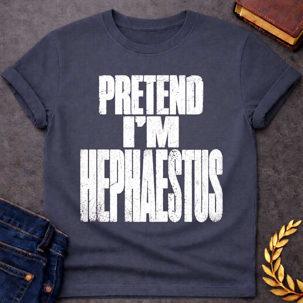 Dark Heather t-shirt with a Pretend I’m Hephaestus Greek mythology design featuring bold distressed white typography on a transparent background. The stacked text reads “PRETEND I’M HEPHAESTUS” in a rugged vintage block font, creating a humorous design inspired by Hephaestus, the Greek god of fire, metalworking, blacksmiths, craftsmanship, and the forge.