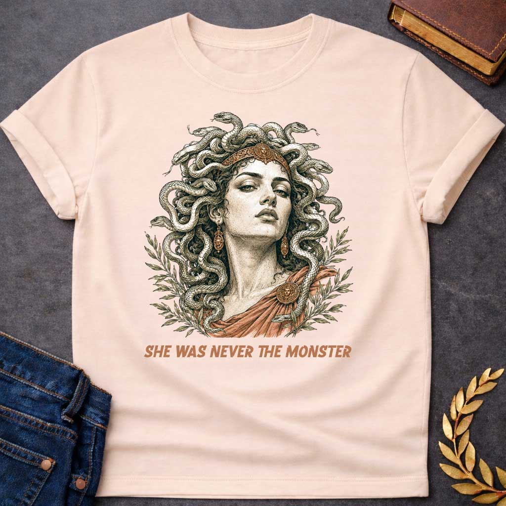 Natural t-shirt with A Detailed vintage engraving-style Greek mythology t-shirt design featuring Medusa with an intense expression, a crown, and numerous snakes twisting through her hair. Olive branches frame the portrait, with bronze and terracotta accents adding an ancient classical feel. Bold text below reads "She Was Never the Monster," creating a dramatic reinterpretation of the Medusa myth.