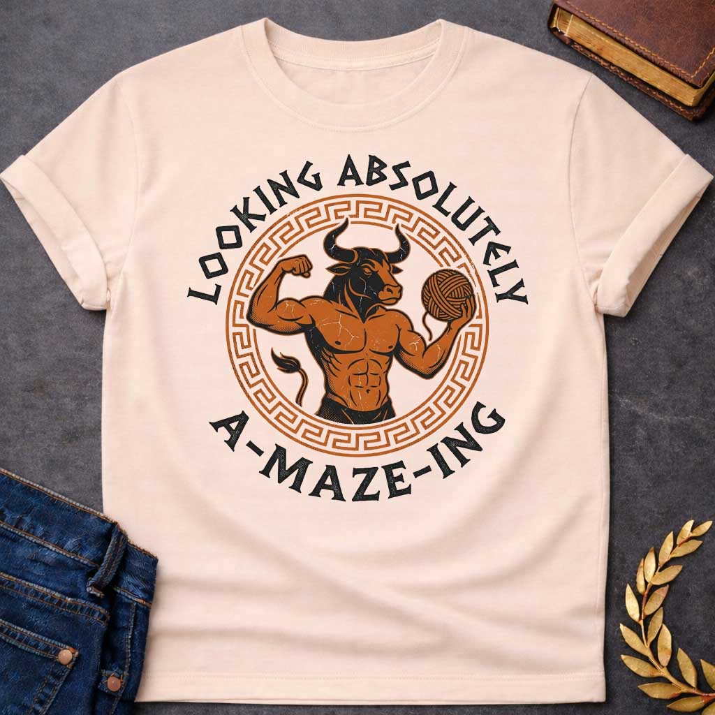Natural T-shirt with a Fitness-themed design of a muscular Minotaur displaying impressive abdominal definition and flexing one arm. The bull-headed figure holds a ball of yarn in the other hand, referencing the mythological thread used to escape the labyrinth. Terracotta orange and brown coloring with defined musculature. Greek key pattern border frames the circular composition. Text reads 'Looking Absolutely A-Maze-Ing' in bold black lettering. Clever wordplay blends gym culture with Greek mythology.