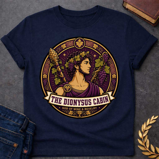 Navy t-shirt with a Dionysus Greek mythology cabin design featuring the god of wine and revelry wearing a grapevine crown and purple robes, surrounded by clusters of grapes, vine leaves, a thyrsus, Greek key patterns, and a wine cup. Purple and gold circular emblem includes the text “The Dionysus Cabin” and “God of Wine & Revelry,”