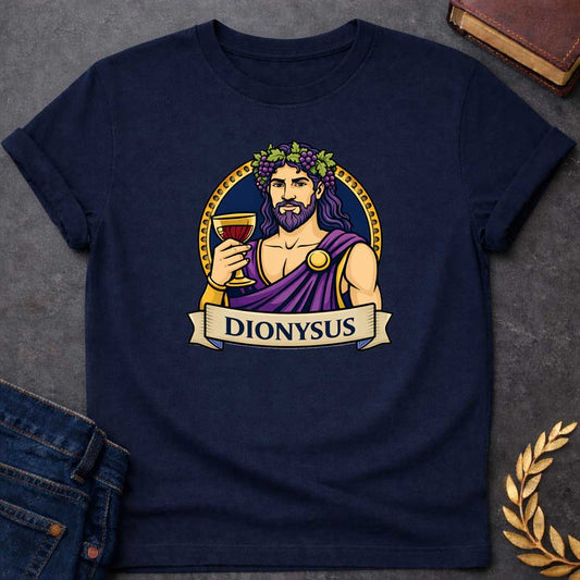 Navy T-shirt graphic featuring a vibrant illustrated portrait of Dionysus, the Greek God of Wine, with long wavy purple hair and a beard, wearing a grape vine and leaf crown adorned with clusters of purple grapes, dressed in a purple draped robe fastened with a gold brooch, raising a golden goblet filled with red wine. He is framed within a gold circular border against a navy background, with a scroll banner below reading "Dionysus," in a bold tattoo-inspired style with navy, gold, and purple tones