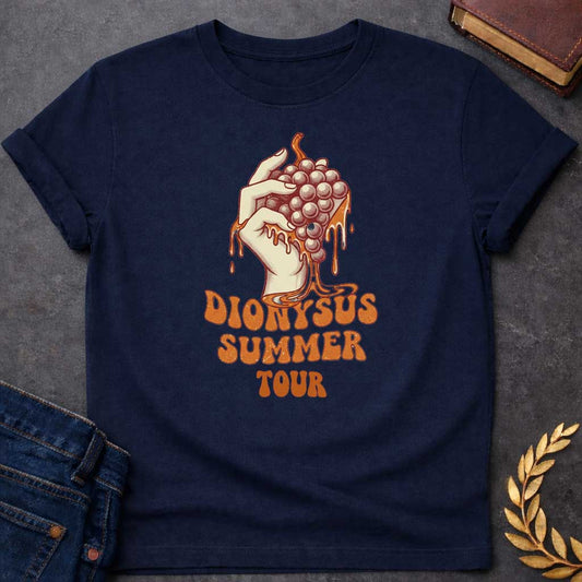 Navy T-shirt graphic featuring a vintage-style illustration of a hand squeezing a bunch of grapes with juice dripping down, rendered in a retro halftone print style in cream and burnt orange tones. Bold groovy retro lettering below reads "Dionysus Summer Tour," inspired by 1970s rock concert merchandise design
