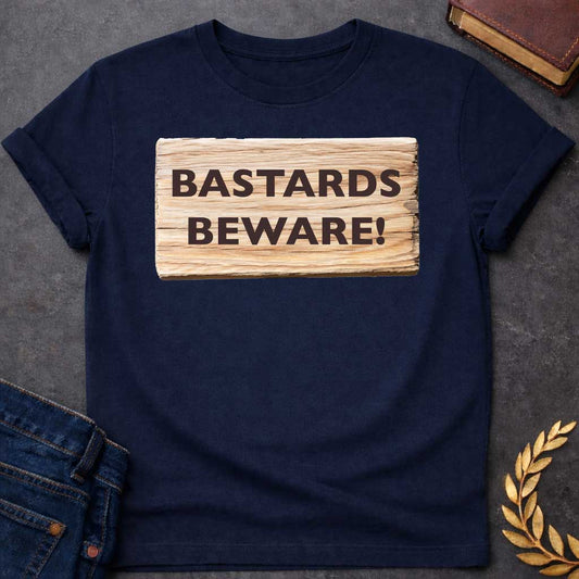Navy T-shirt graphic featuring a realistic illustration of a weathered and splintered wooden plank sign with bold dark brown text reading "Bastards Beware!" in a humorous nod to Hera, the Greek Queen of the Gods, known for her jealous wrath toward Zeus's illegitimate children