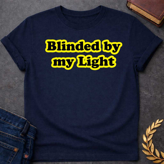 Navy T-shirt Streetwear graphic design featuring the phrase "Blinded by my Light" in bold black bubble typography with a vibrant yellow glow. Retro-style aesthetic inspired by Greek mythology and Apollo, the god of light