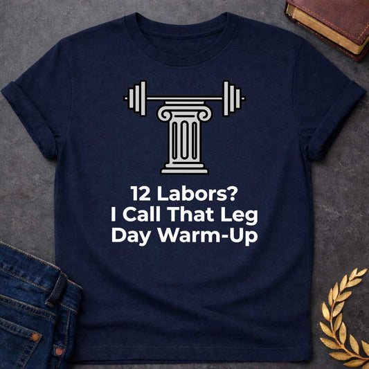 Navy T-shirt with a graphic design. At the top, there is a gray illustration of a classical Greek column supporting a barbell with weight plates on both sides. Below the illustration, the white text reads: "12 Labors? I Call That Leg Day Warm-Up"