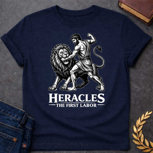 Navy T-shirt. The illustration features a woodcut-style depiction of the Greek hero Heracles wrestling the Nemean lion. Below the artwork, the text reads in white "HERACLES" in a large, distressed serif font, followed by the smaller subtitle "THE FIRST LABOR,"