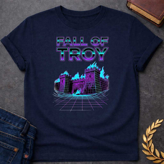 Navy T-shirt featuring bold chrome 3D outlined text reading "Fall of Troy" above a retro vaporwave-style illustration of the burning city of Troy depicted as a purple halftone castle engulfed in bright teal flames, set on a glowing teal perspective grid floor — referencing the legendary fall of Troy from Greek mythology, rendered in a vivid 1980s retro synthwave aesthetic in purple and teal tones