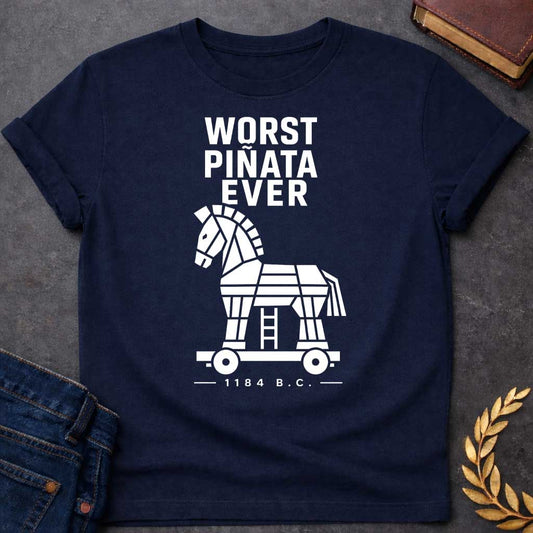 Navy T-shirt with a graphic in white featuring bold condensed sans-serif text reading "Worst Piñata Ever" above a detailed flat geometric white silhouette illustration of the Trojan Horse on a wheeled platform with a visible ladder underneath, with a small datestamp below reading "— 1184 B.C. —" — a humorous reference to the Greek legend of the Trojan War