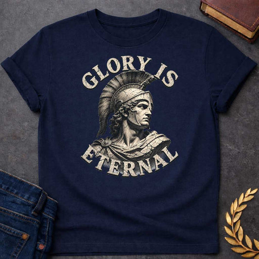 Navy T-Shirt with a classical illustration of a Greek warrior in profile, rendered in sepia tones with weathered, cracked texture. The figure wears an ornate Corinthian helmet with black horsehair crest, long curly hair, and armor with a draped cloak. The warrior gazes stoically with classical features. Distressed serif letters spell 'GLORY IS' above and 'ETERNAL' below. The design has a vintage, monumental quality reminiscent of ancient statuary, emphasizing themes of heroism, honor, and timeless legacy.