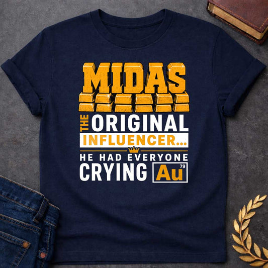 Navy t-shirt with A Bold typographic Greek mythology design featuring stacked gold bar lettering spelling "MIDAS" above the phrase "The Original Influencer... He Had Everyone Crying Au." The design uses distressed black and metallic gold typography with a small crown icon and a gold-themed chemical element "Au" symbol, creating a humorous King Midas pun in a vintage-inspired graphic style.