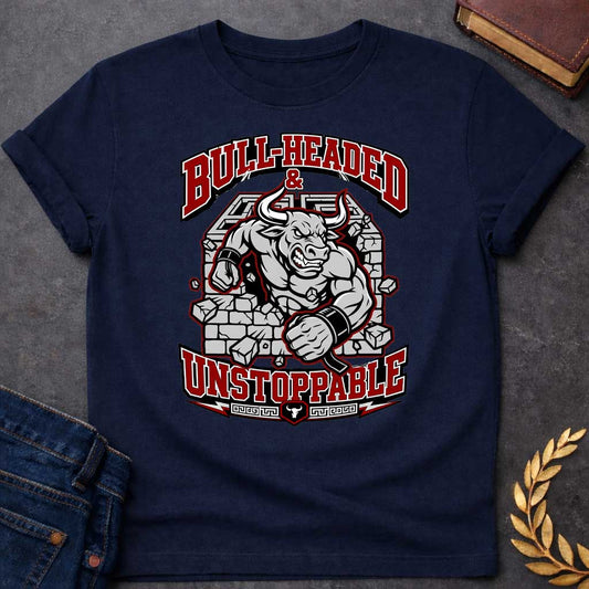 Navy T-shirt with a High-impact sports design featuring a muscular Minotaur bursting through a crumbling stone wall in red, gray, and white. The aggressive bull-headed figure displays defined musculature and determination. Text reads 'Bull-Headed & Unstoppable' in bold red and black lettering. Greek key pattern and bull symbol anchor the bottom. Combines Greek mythology with modern gym and sports culture, celebrating stubborn strength and unstoppable power.