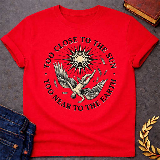 Red t-shirt with a vintage engraved-style illustration. A winged figure of Icarus plummets downward upside down as loose feathers drift through the air beneath a large, radiating sun emblem. Encircling the detailed central artwork, bold black serif text reads "TOO CLOSE TO THE SUN" along the top arch and "TOO NEAR TO THE EARTH" along the bottom curve.