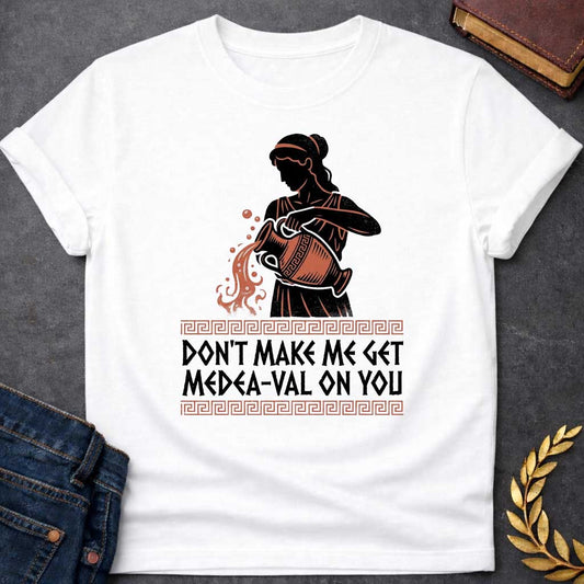 White T-shirt with A Silhouetted figure of Medea, legendary Greek sorceress, rendered in black and rust-red. She wears classical robes and headband while holding an ornate cauldron with magical flames and sparks bursting forth. Greek key pattern borders frame the design. Text reads 'Don't Make Me Get Medea-Val On You' - wordplay combining her name with modern slang. Celebrates Medea's fearsome magical and destructive powers with contemporary humor.