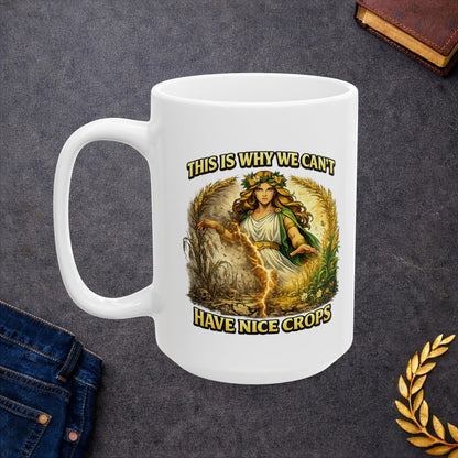 White ceramic mug with a dramatic illustration of Demeter, the Greek goddess of agriculture, standing over a split field. A glowing lightning strike cracks down the center, dividing flourishing, green crops on the right from dead, withered stalks and skulls on the left. Arching text above and below reads "THIS IS WHY WE CAN'T HAVE NICE CROPS" in a bold, weathered yellow font. The design has an intense, mythical comic art style.