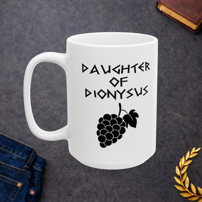White ceramic mug featuring a minimalist, Greek-inspired graphic in black ink on a white background. The design reads 'DAUGHTER OF DIONYSUS' in a stylized, angular font, positioned above a clean, line-art graphic of a cluster of grapes hanging from a vine with leaves.