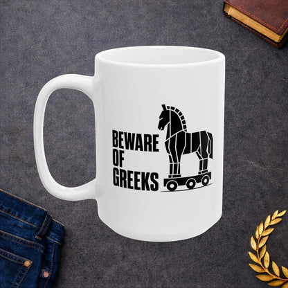 White ceramic mug with a minimalist black-and-white graphic featuring a stylized, geometric silhouette of the Trojan Horse on a wheeled platform. To the left of the horse, the text "BEWARE OF GREEKS" is written vertically in a bold, stacked, black sans-serif font. The design uses clean lines and high contrast on a plain background, offering a modern, minimalist take on the classic Greek mythological tale.