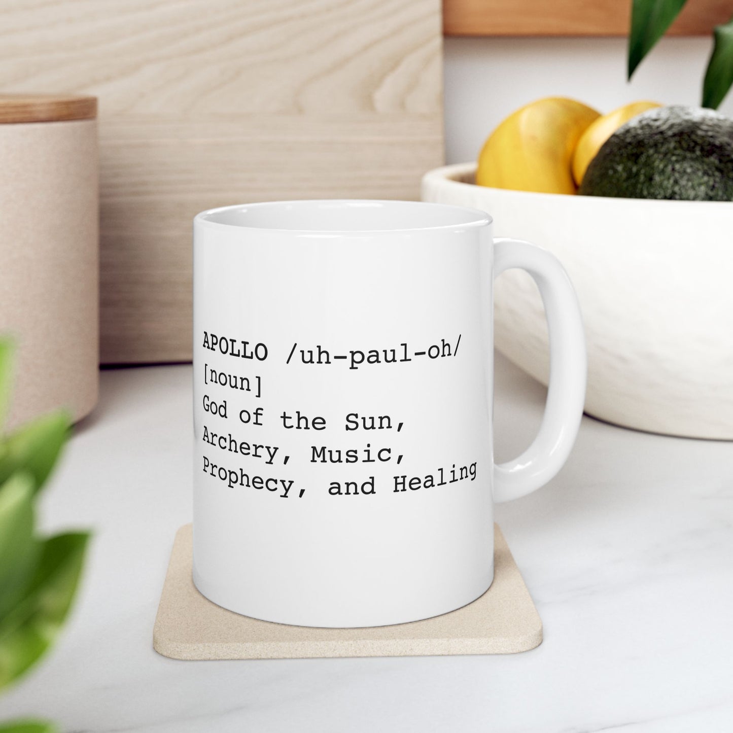 White ceramic mug featuring a dictionary-style definition graphic in black text on a white background. The text reads: 'APOLLO /uh-paul-oh/ [noun] God of the Sun, Archery, Music, Prophecy, and Healing.'