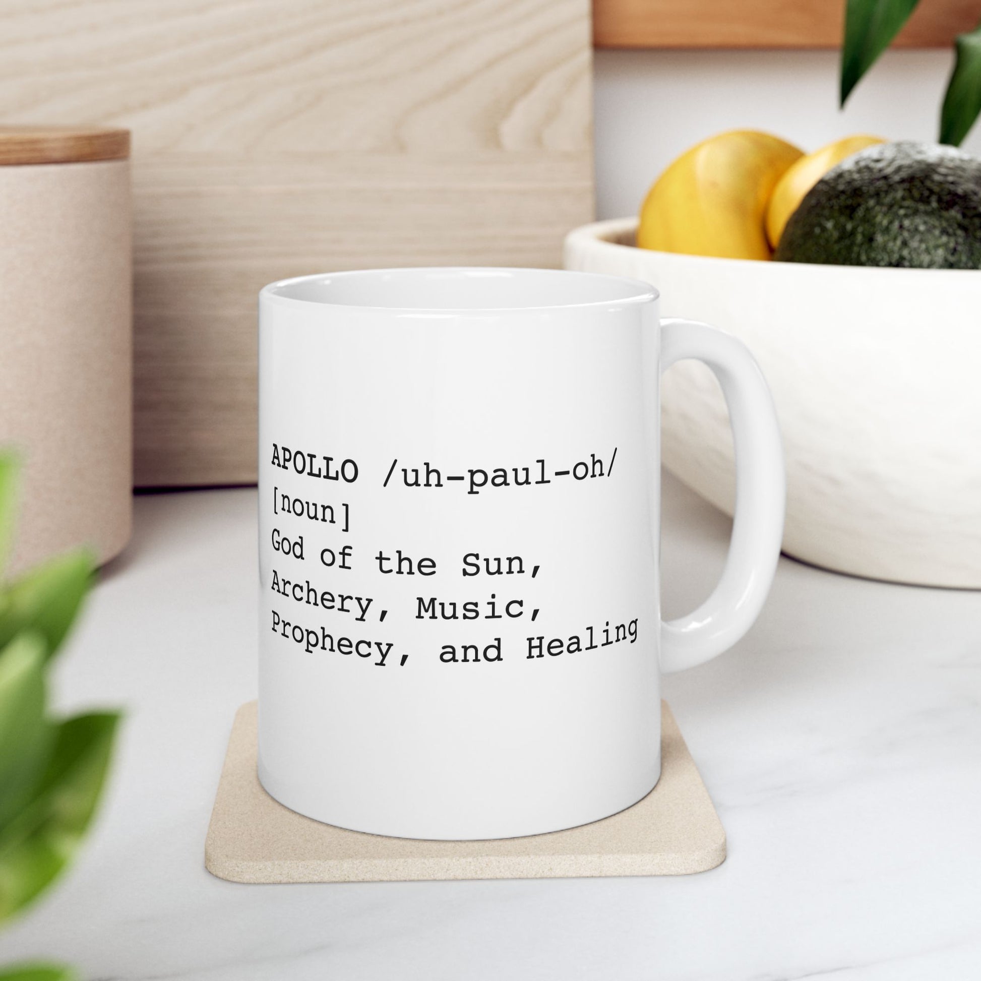 White ceramic mug featuring a dictionary-style definition graphic in black text on a white background. The text reads: 'APOLLO /uh-paul-oh/ [noun] God of the Sun, Archery, Music, Prophecy, and Healing.'