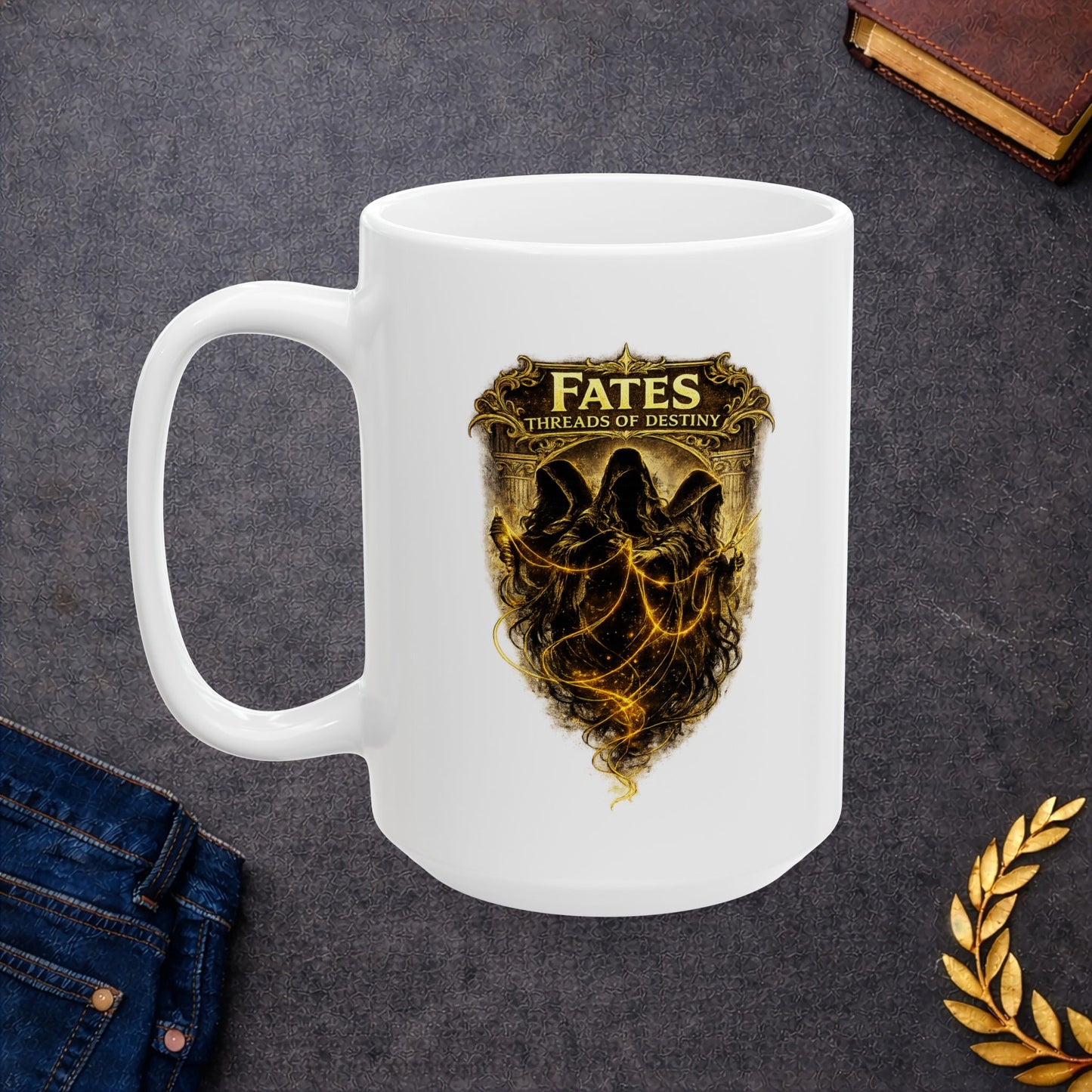 White ceramic mug with a dramatic, gold-toned illustration featuring the three Fates as hooded, shadowy figures. They are shown spinning, measuring, and cutting glowing golden threads of light against a dark background. Above them, a decorative golden frame contains the words "FATES" and "THREADS OF DESTINY." The artwork has a mystical, high-contrast aesthetic with intricate classical details and ethereal lighting.