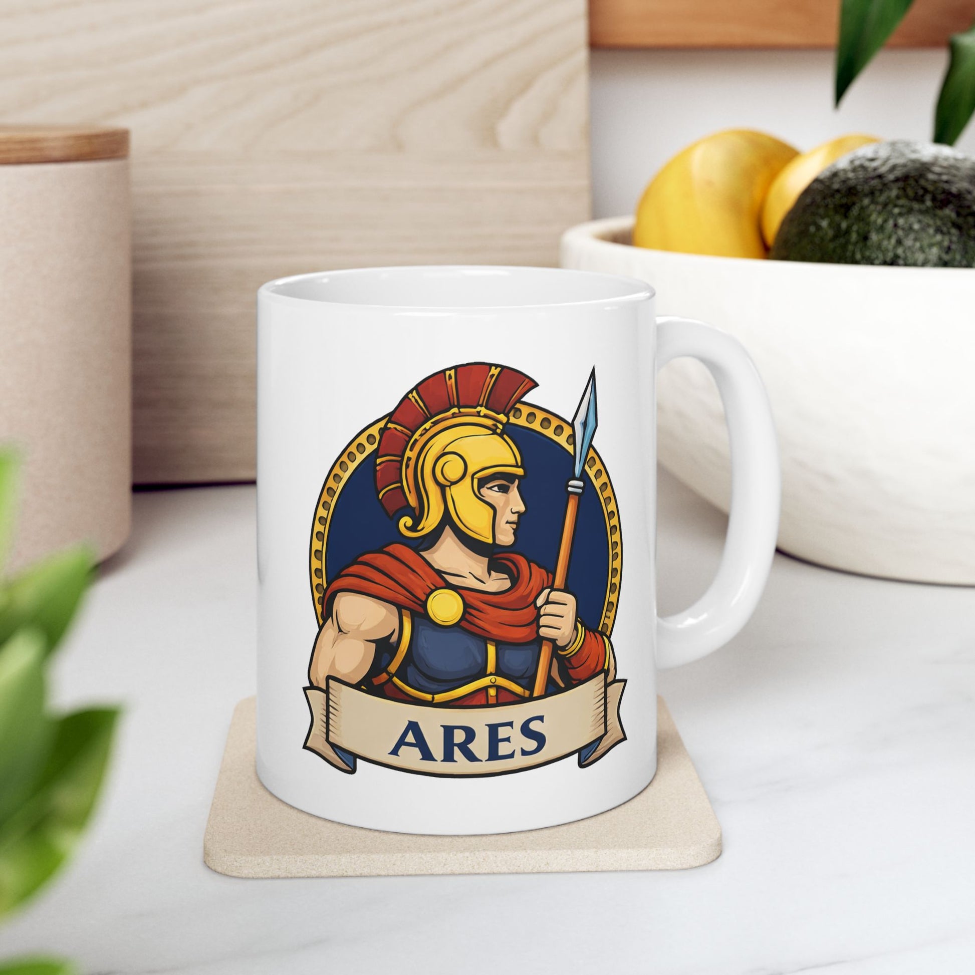 White ceramic mug with a circular emblem of the Greek god Ares in a modern vector art style. He is depicted in profile, wearing a golden Spartan-style helmet with a red crest and a red cape over blue armor. He holds a tall spear against a dark blue background bordered by a gold dotted ring. A tan parchment banner at the bottom displays the name "ARES" in bold, dark blue capital letters.