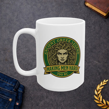Funny Greek mythology mug design featuring a bold vintage badge with Medusa's stern face surrounded by writhing snakes. The circular emblem reads "Ancient Greek Legend" across the top and "Making Men Hard" on a banner below, with "700 BC" at the bottom. The design uses classic green, gold, and olive tones in a retro emblem style, combining mythology with humorous wordplay.