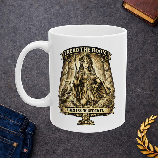 White ceramic mug with a detailed sepia-toned illustration of the goddess Athena in battle armor, holding a spear among ruined Greek columns. An owl perches on a pedestal beside her. Banners above and below read "I READ THE ROOM" and "THEN I CONQUERED IT." The design features an intricate, etched vintage style with classical motifs, combining a modern empowering slogan with ancient Greek aesthetics.