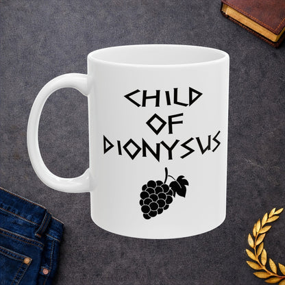 White ceramic mug featuring a minimalist, Greek-inspired graphic in black ink on a white background. The design reads 'CHILD OF DIONYSUS' in a stylized, angular font, positioned above a clean, line-art graphic of a cluster of grapes hanging from a vine with leaves.