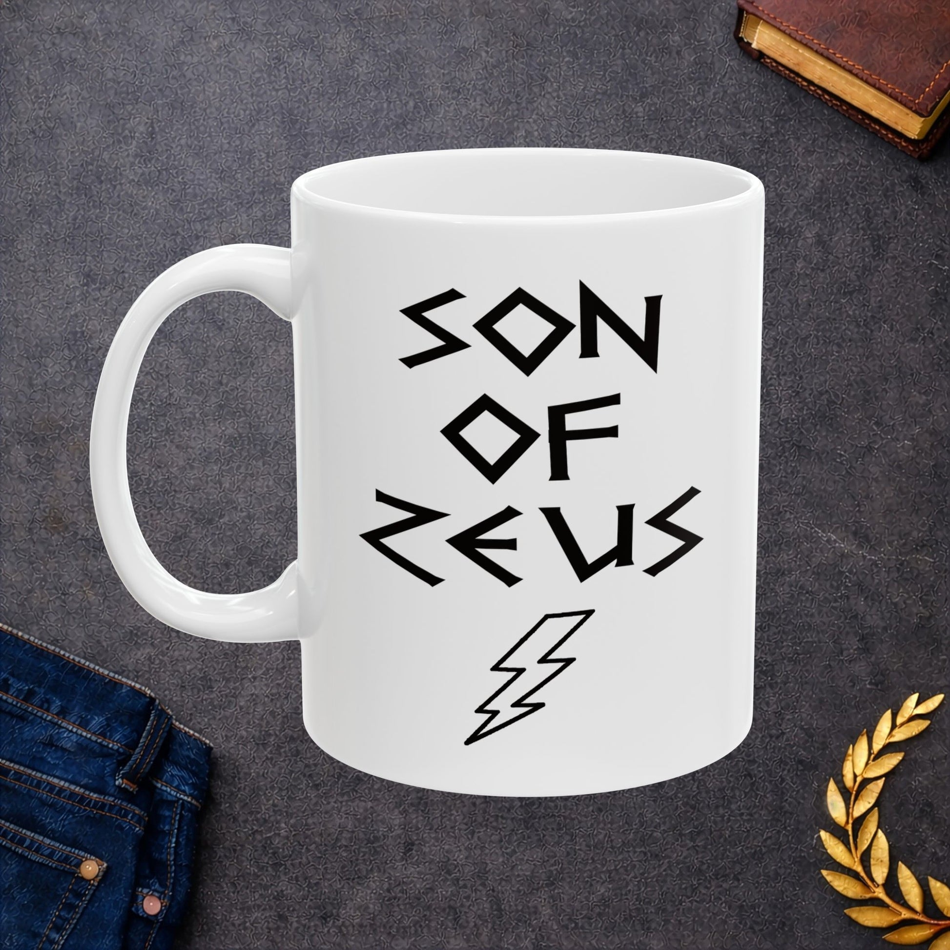 A minimalist black graphic for a white ceramic mug featuring a large, central outline of a lightning bolt. Above the bolt, the text "SON OF ZEUS" is written in a sharp, angular font inspired by ancient Greek inscriptions. The entire design is rendered in a clean, high-contrast black outline style.