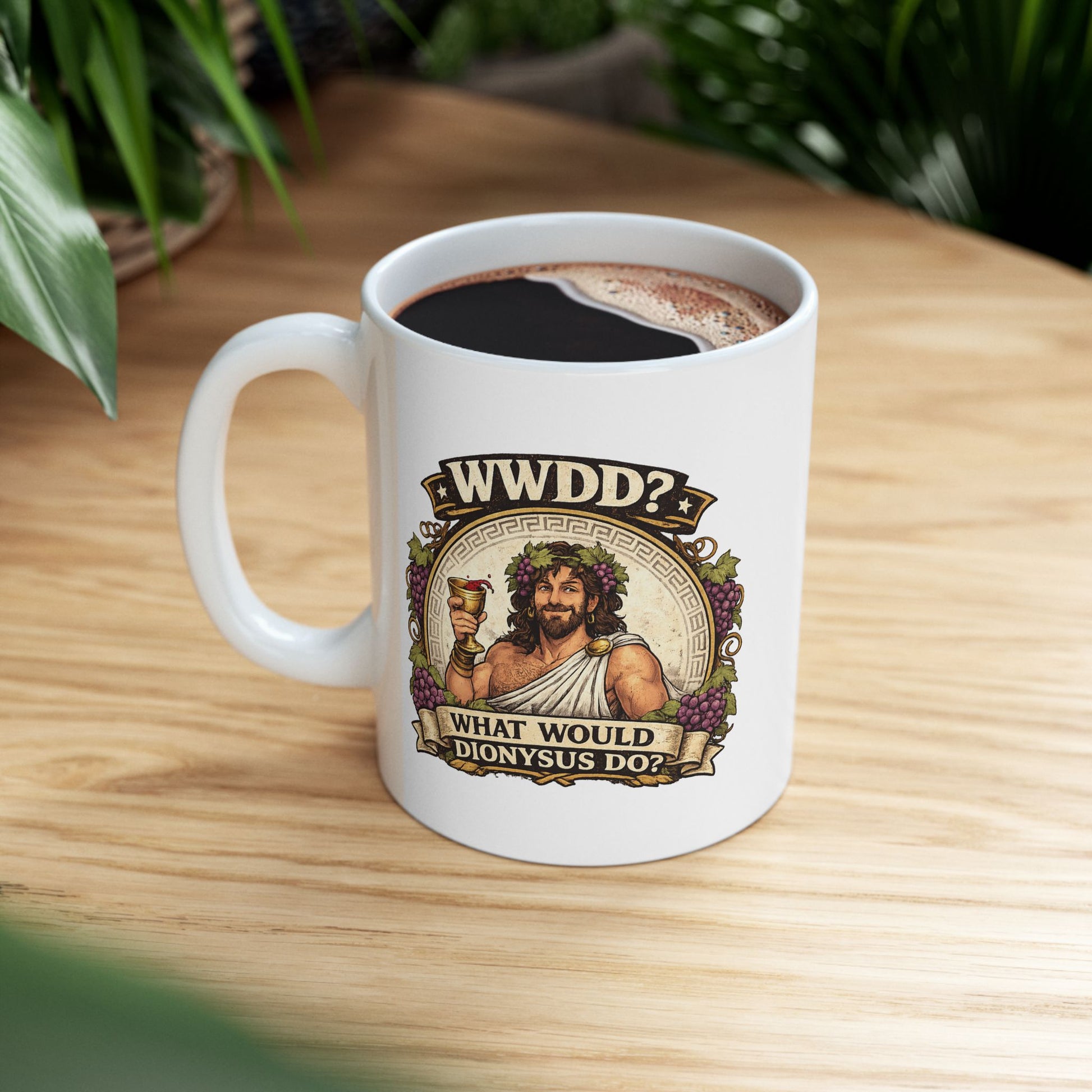 White ceramic mug with a vintage-style illustration of Dionysus, the Greek god of wine, smiling as he raises a golden goblet splashing with red wine. He wears a toga, a laurel wreath interwoven with purple grapes, and is framed by a circular Greek key pattern and clusters of grapes. Banners above and below read "WWDD?" and "WHAT WOULD DIONYSUS DO?" The design features a detailed, textured classical aesthetic.