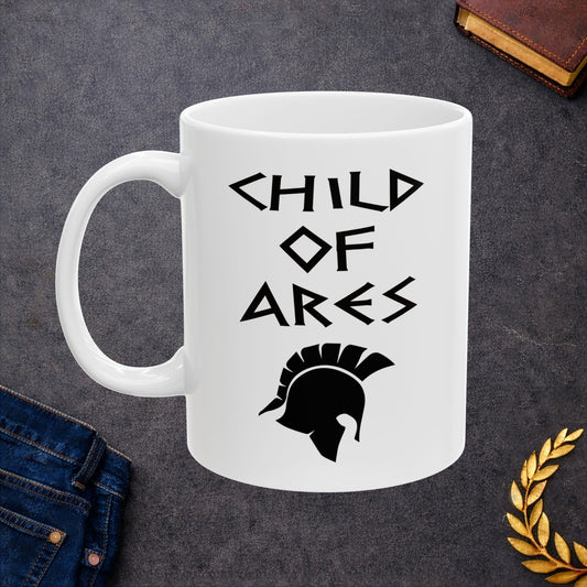 White ceramic mug featuring a minimalist, Greek-inspired graphic in black ink on a white background. The design reads 'CHILD OF ARES' in a stylized, angular font, positioned above a clean, line-art graphic of a Spartan-style plumed warrior helmet.