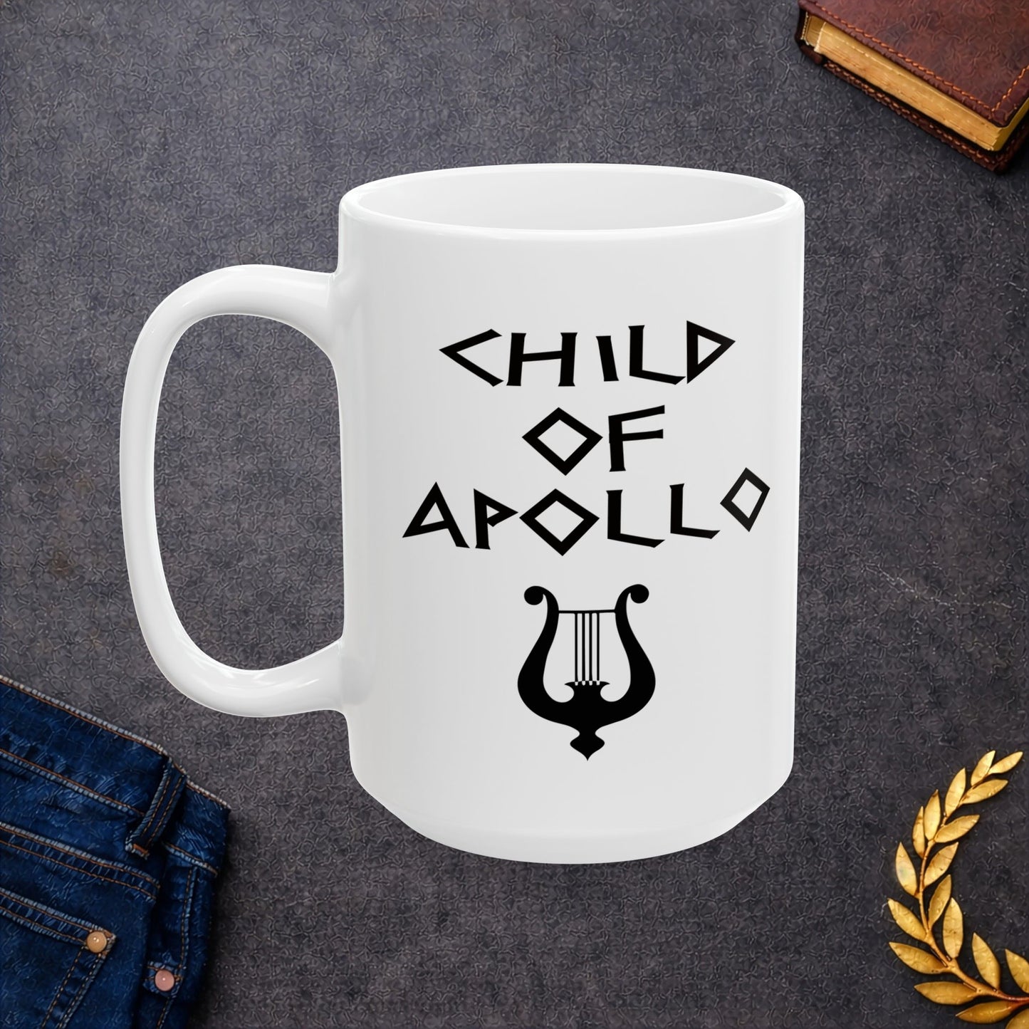 White ceramic mug featuring a minimalist, Greek-inspired graphic in black ink on a white background. The design reads 'CHILD OF APOLLO' in a stylized, angular font, positioned above a clean, line-art graphic of a classical lyre.