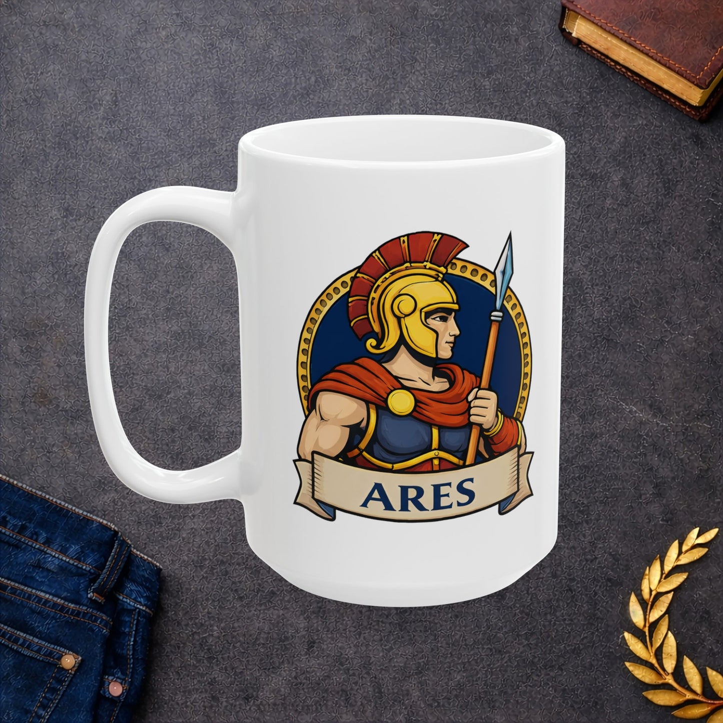 White ceramic mug with a circular emblem of the Greek god Ares in a modern vector art style. He is depicted in profile, wearing a golden Spartan-style helmet with a red crest and a red cape over blue armor. He holds a tall spear against a dark blue background bordered by a gold dotted ring. A tan parchment banner at the bottom displays the name "ARES" in bold, dark blue capital letters.