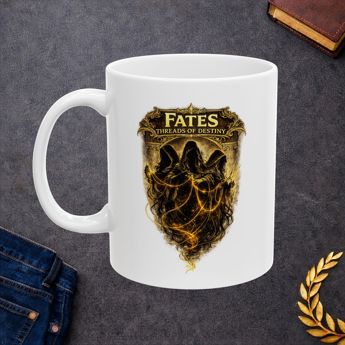 White ceramic mug with a dramatic, gold-toned illustration featuring the three Fates as hooded, shadowy figures. They are shown spinning, measuring, and cutting glowing golden threads of light against a dark background. Above them, a decorative golden frame contains the words "FATES" and "THREADS OF DESTINY." The artwork has a mystical, high-contrast aesthetic with intricate classical details and ethereal lighting.