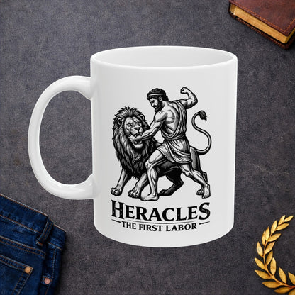 White ceramic mug with a striking black-and-white linocut illustration depicting the Greek hero Heracles wrestling the Nemean Lion. The muscular hero forces his arm into the lion’s open jaws while raising his fist to strike. Below the dynamic scene, bold text reads "HERACLES" followed by a sub-caption that reads "THE FIRST LABOR." The design has a classic, high-contrast vintage woodcut engraving style.