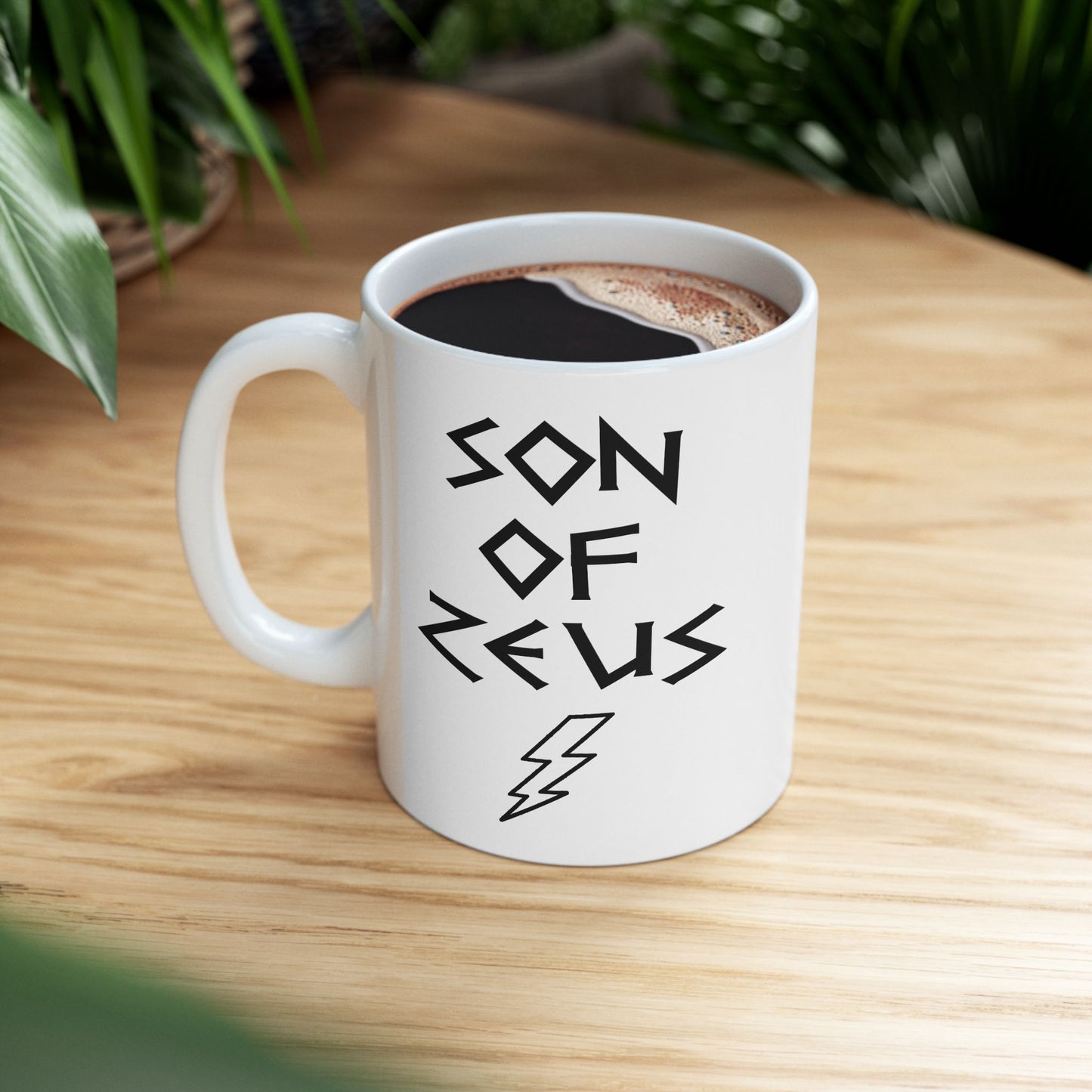 A minimalist black graphic for a white ceramic mug featuring a large, central outline of a lightning bolt. Above the bolt, the text "SON OF ZEUS" is written in a sharp, angular font inspired by ancient Greek inscriptions. The entire design is rendered in a clean, high-contrast black outline style.